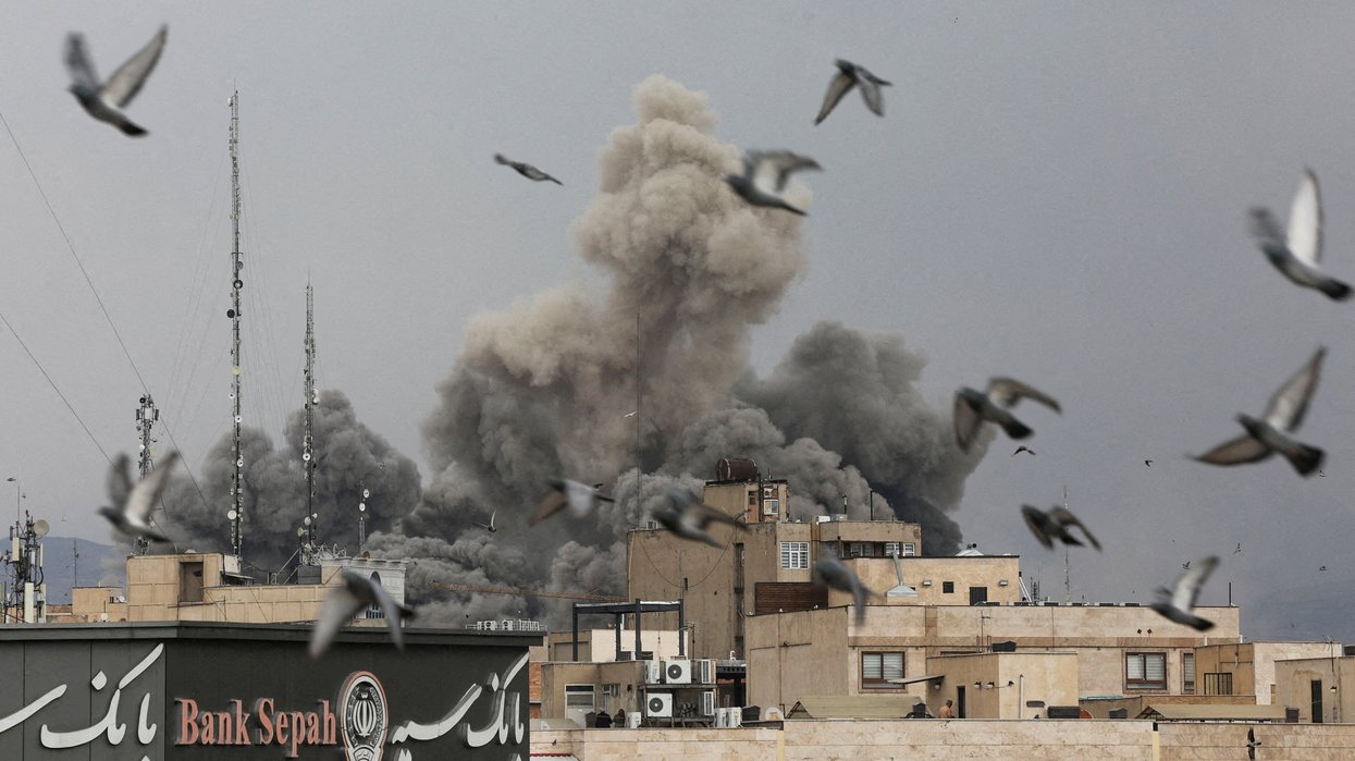 Birds fly as smoke rises following an explosion, after Israel and the U.S. launched strikes on Iran,