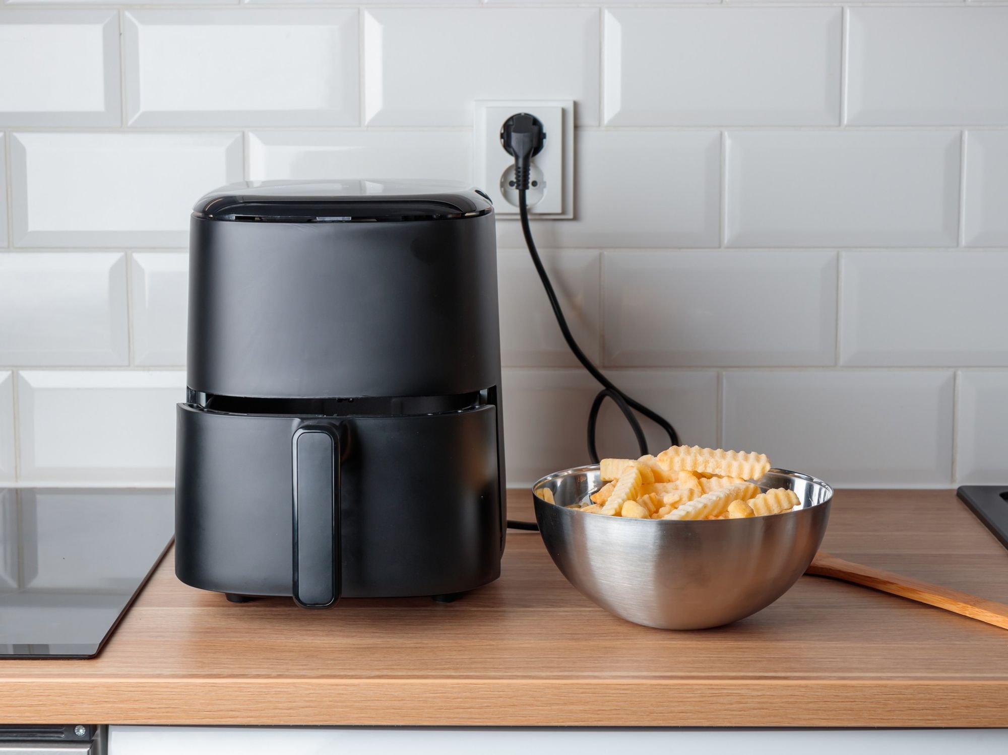 Black air fryer and bowl of chips
