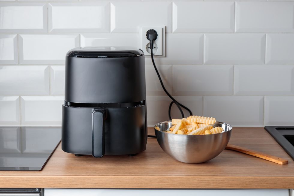 Black air fryer and bowl of chips