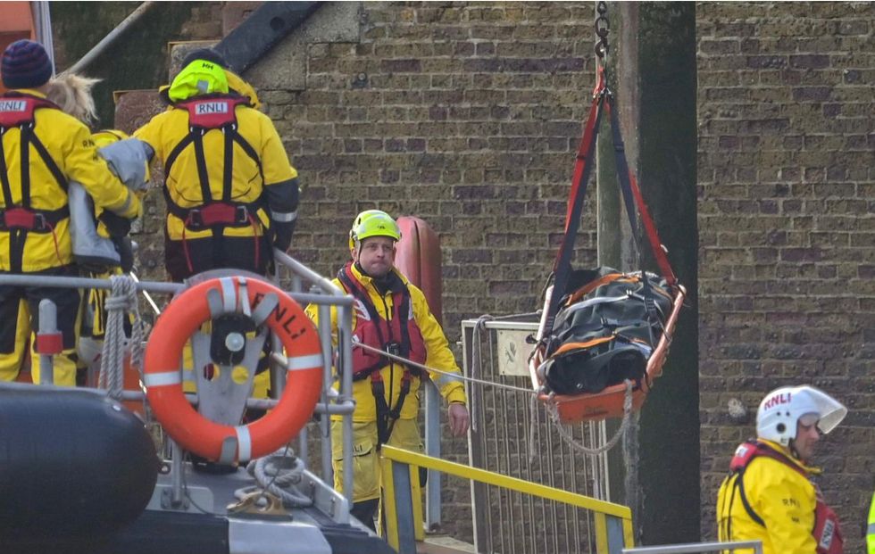 Body bags are lifted to shore in Kent this afternoon after the migrant vessel capsized overnight