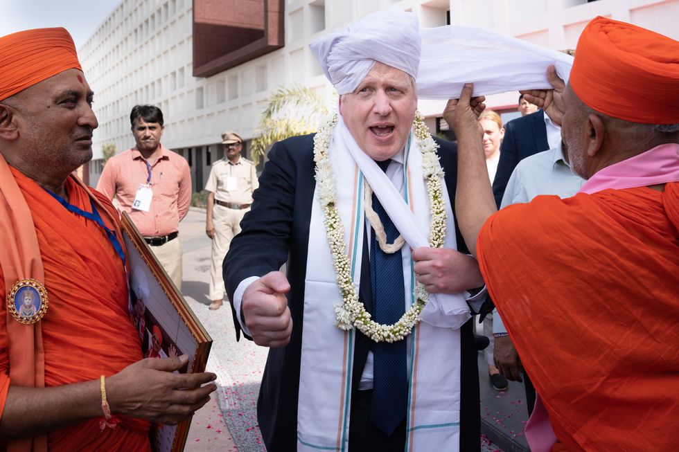 Boris Johnson having a turban placed on his head at Gujarat Bio Technology University.
