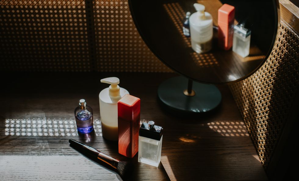 Bottles of hair product on a wooden table in front of a circular mirror