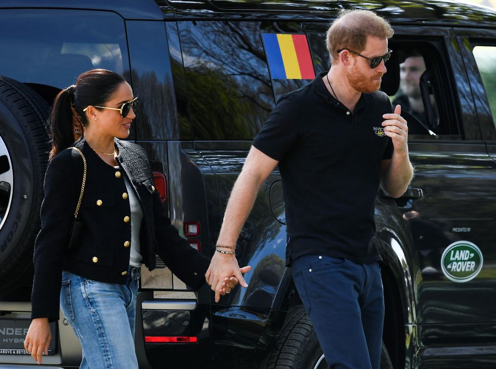 Britain's Prince Harry and Meghan, Duchess of Sussex, hold hands and walk as they attend the Land Rover Driving Challenge of the Invictus Games in The Hague