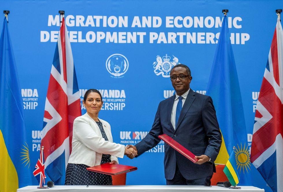 British Home Secretary Priti Patel shakes hands with Rwandan Foreign Minister Vincent Birutaare after signing the partnership agreement at a joint news conference in Kigali.