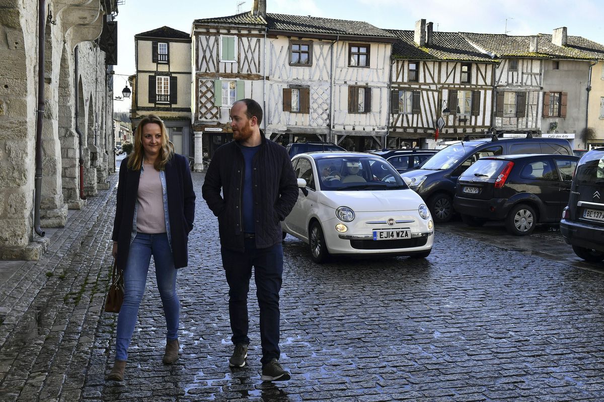 British residents Maura McGuirk (L) and James McConnel, who recently moved in Eymet, southwestern France, walk on the central square