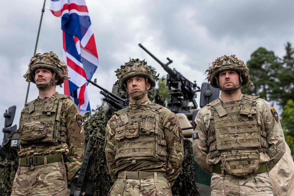 British soldiers stand in front of a military vehicle