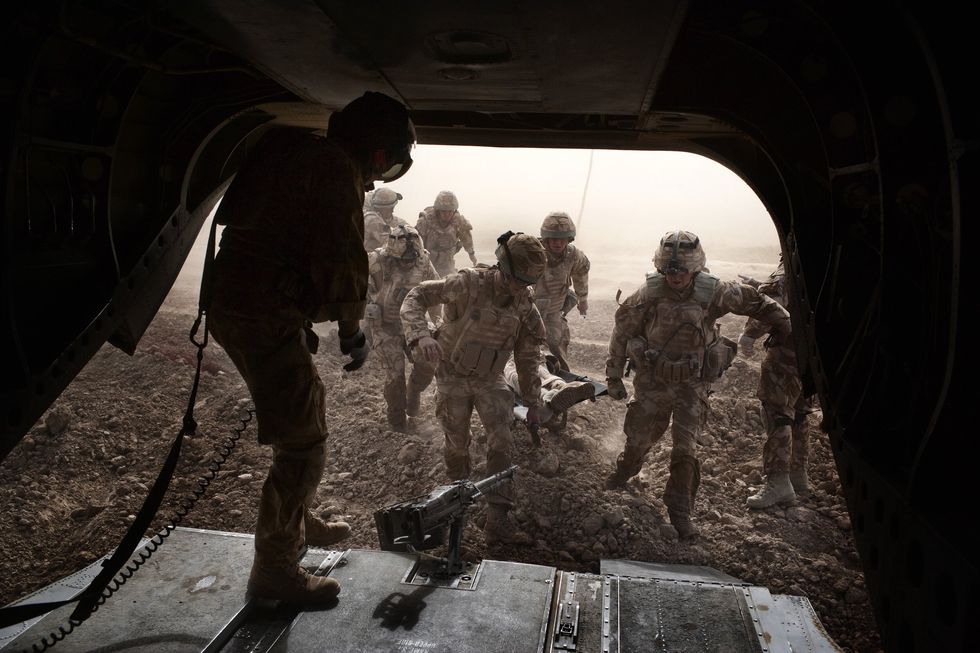 British troops carry a wounded soldier on a stretcher into a Royal Air Force Chinook