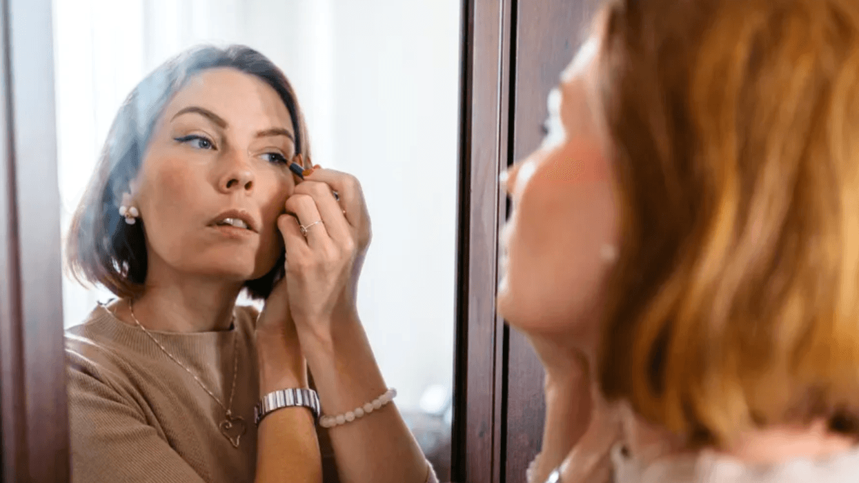 Brunette woman applying eyeliner in the mirror