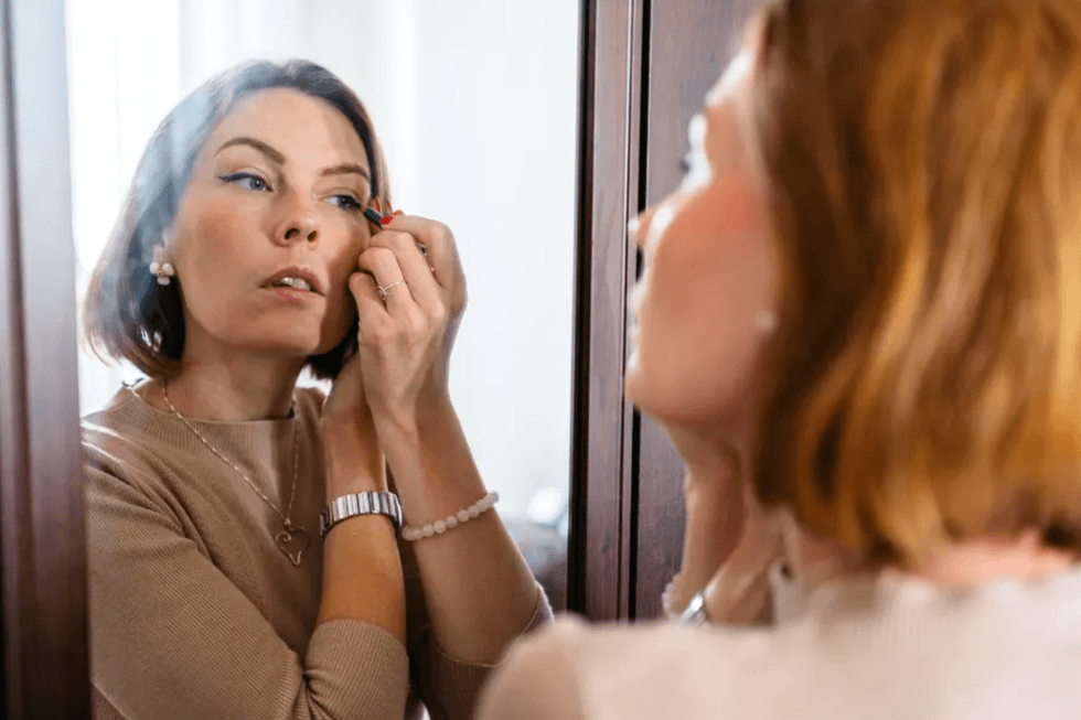 Brunette woman applying eyeliner in the mirror