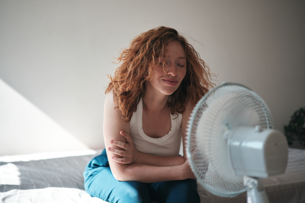 Brunette woman sitting near a white fan