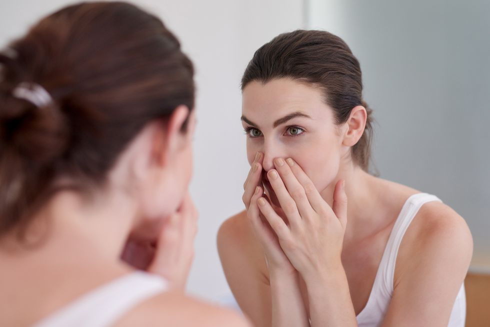 Brunette woman washing her face in the mirror