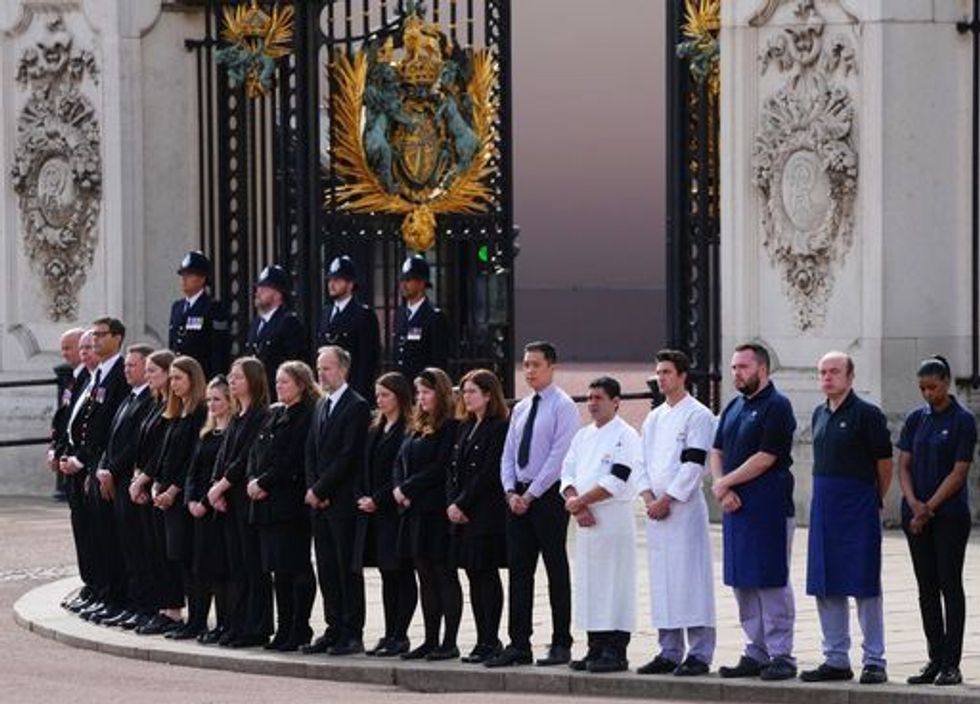 Buckingham Palace household staff pay their respects outside Buckingham Palace during the coffin procession from Westminster Abbey to Wellington Arch, London. Picture date: Monday September 19, 2022.