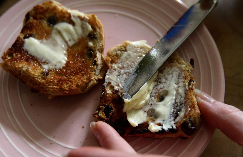 Butter being spread on hot cross bun