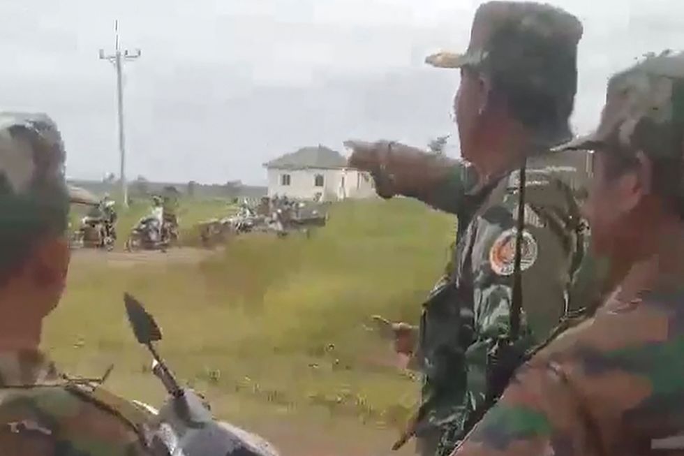 Cambodian soldiers look at people evacuate from along the Cambodia-Thailand border after Cambodian and Thai troops exchanged fire