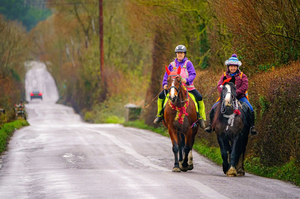 Car driving on a rural road with horse riders