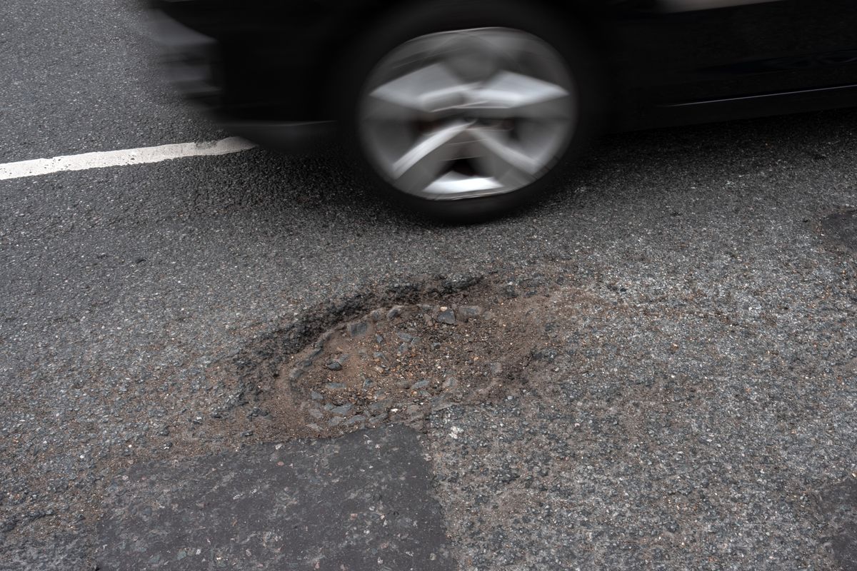 Car driving past pothole in road
