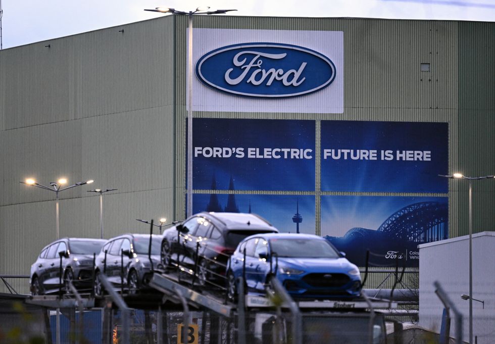 Cars of US car manufacturer Ford car stand on a lorry transporter in front of their logo at the Ford plant in K\u00f6ln, Germany
