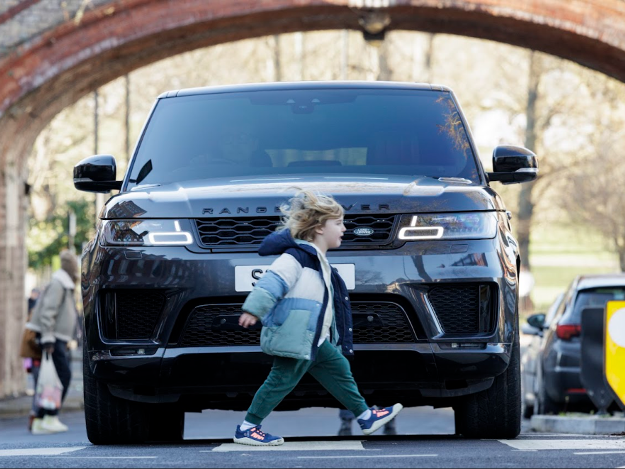 Child crossing road with SUV in background