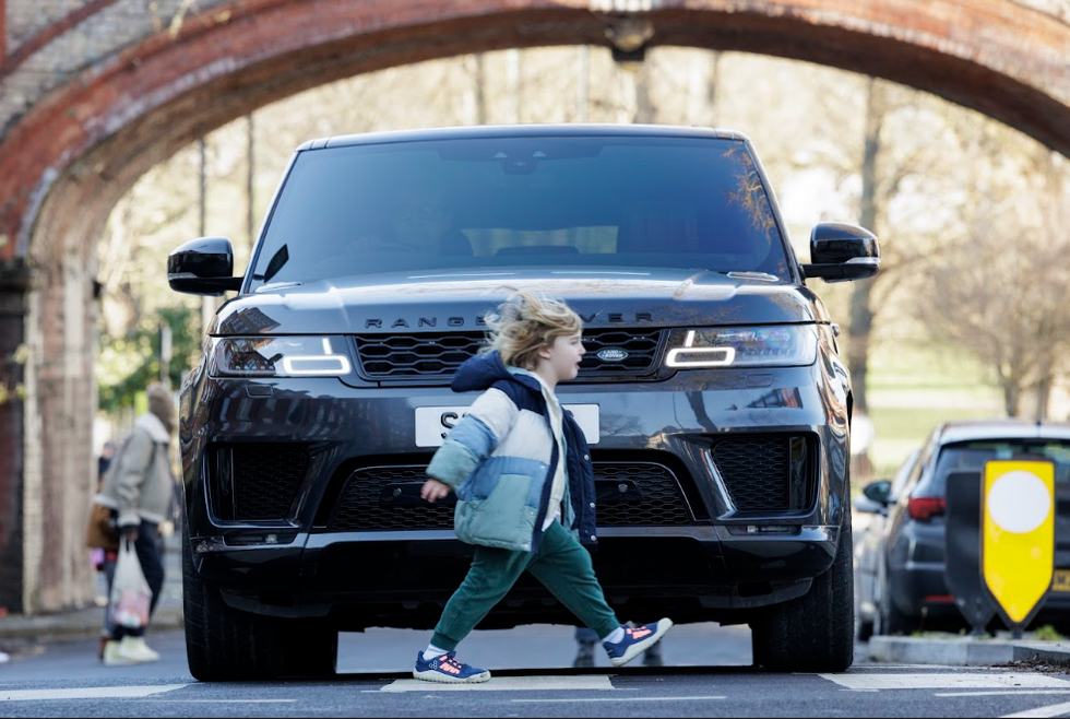 Child crossing road with SUV in background