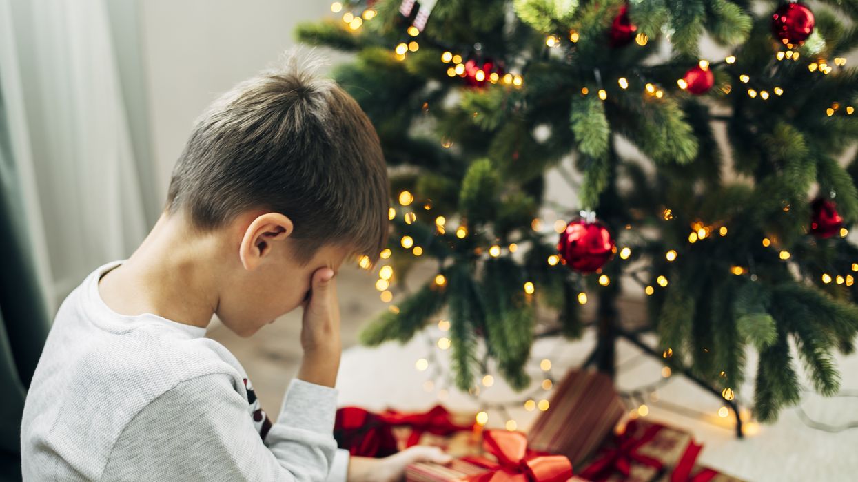 Child sobbing in front of Christmas tree