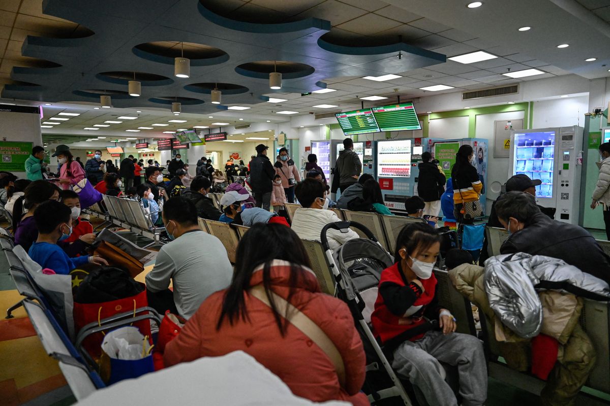 Children and their parents wait at an outpatient area at a children hospital in Beijing on November 23