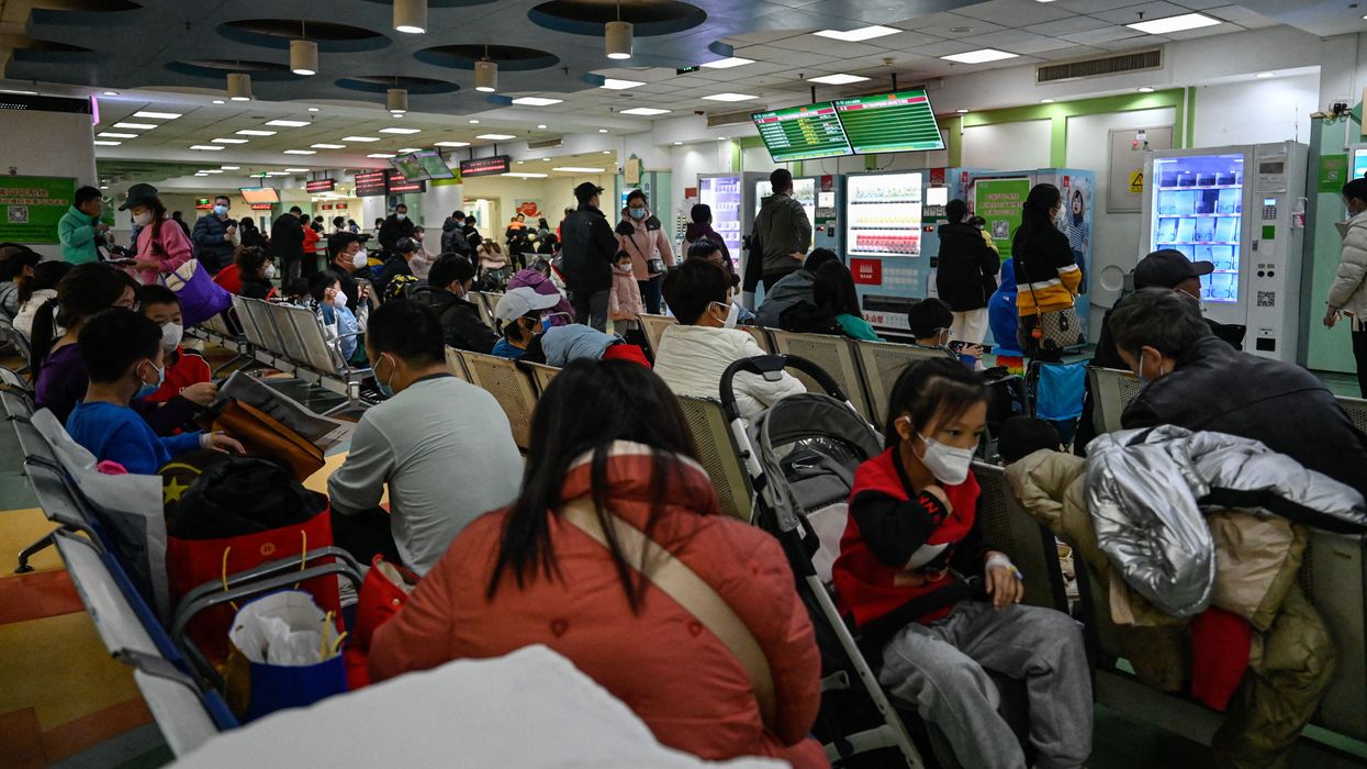 Children and their parents wait at an outpatient area at a children hospital in Beijing on November 23
