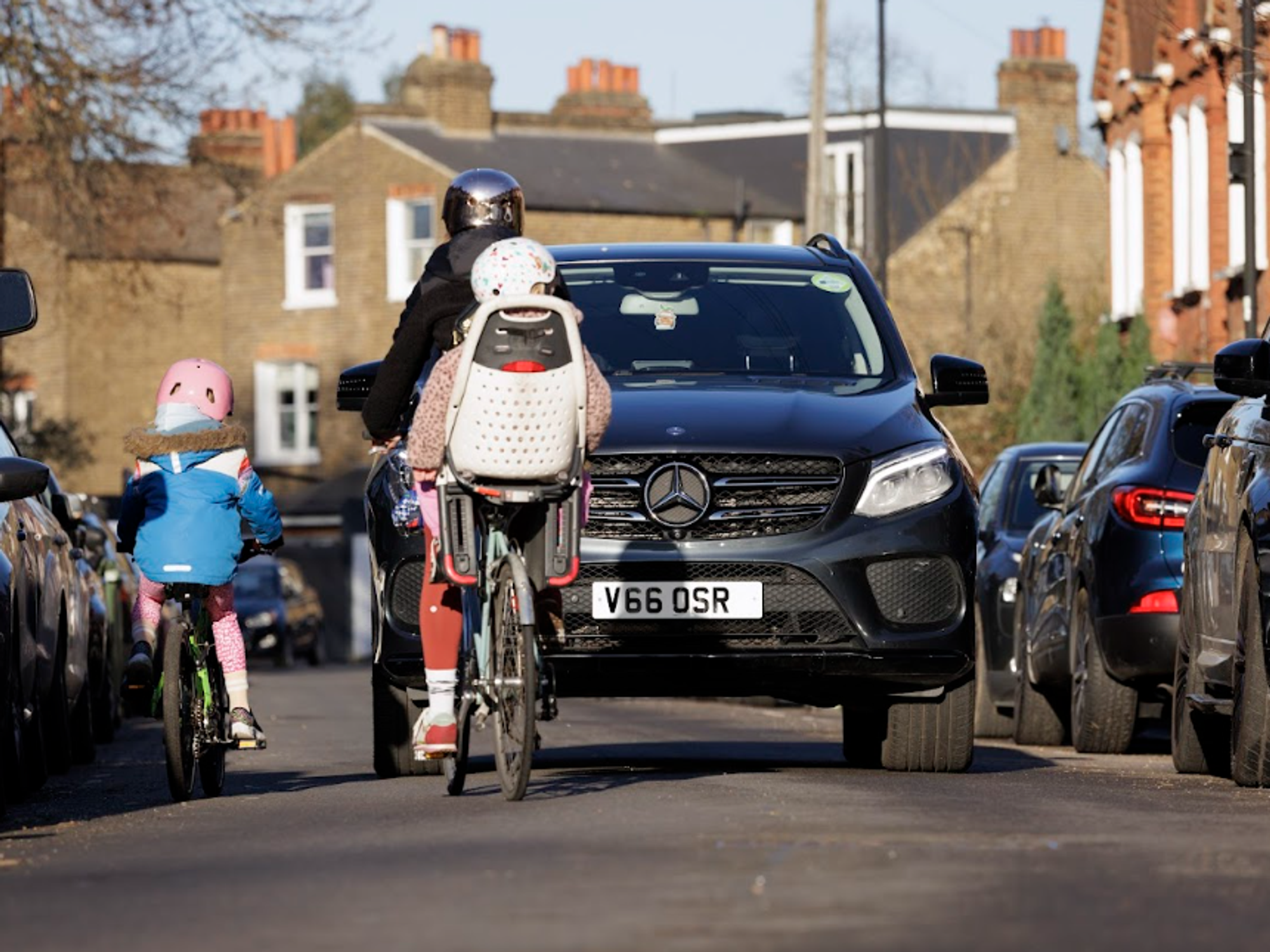 Children on bikes near SUV driving on roads