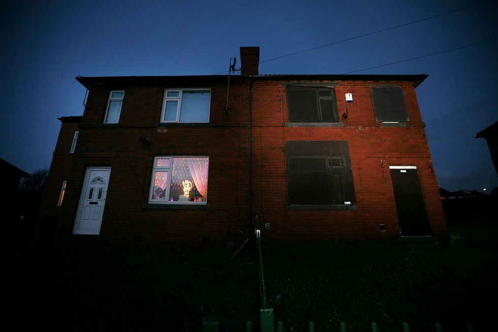 Christmas decorations light up the house next door to the boarded up home of nine-year-old kidnap victim Shannon Matthews which lays empty in Moorside Road