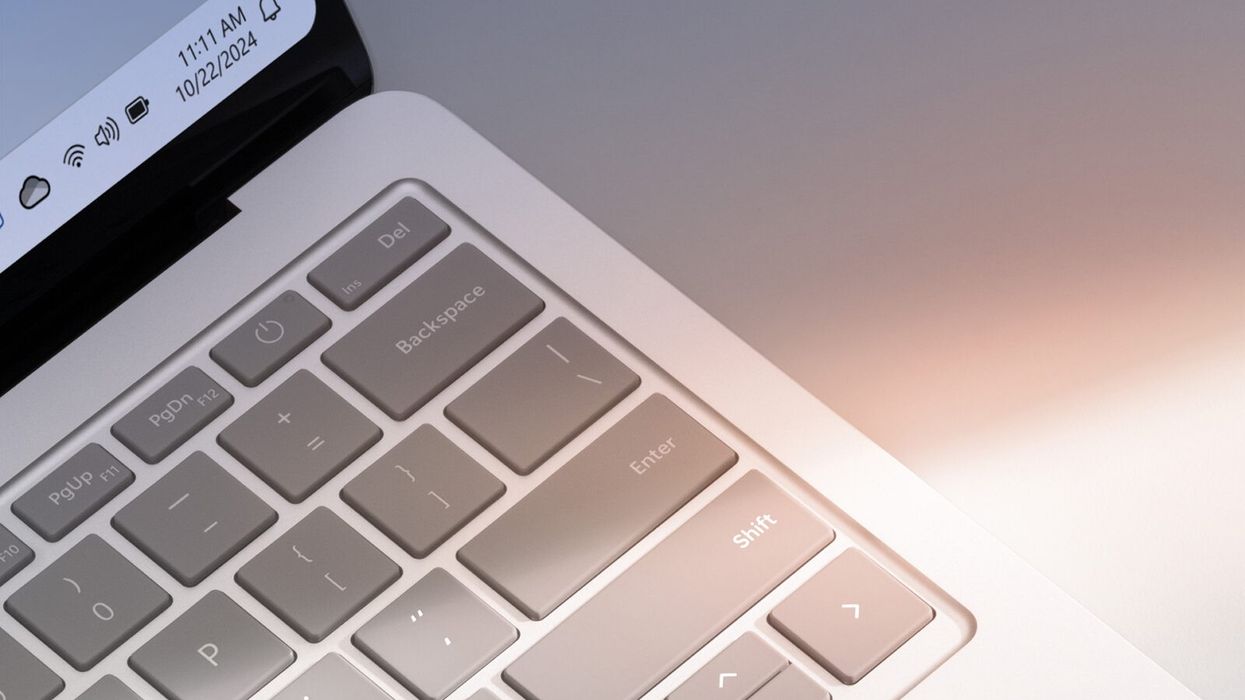 close-up shot of a windows 11 laptop keyboard with a hint of the operating system shown in the corner of the screen