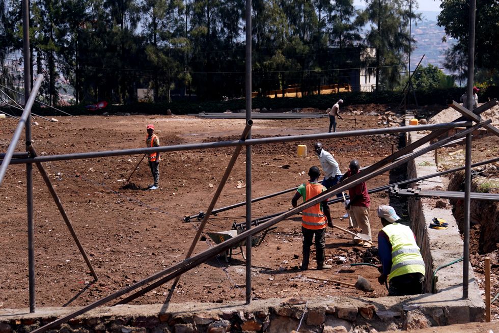 Construction workers shovel earth on the site of a basketball court that will be built next to the Hope Hostel