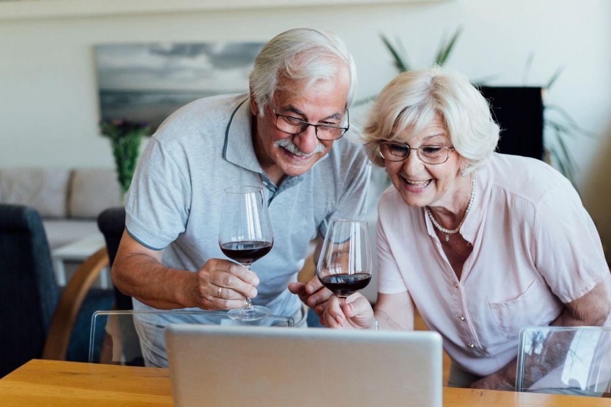 Couple at laptop celebrating with wine