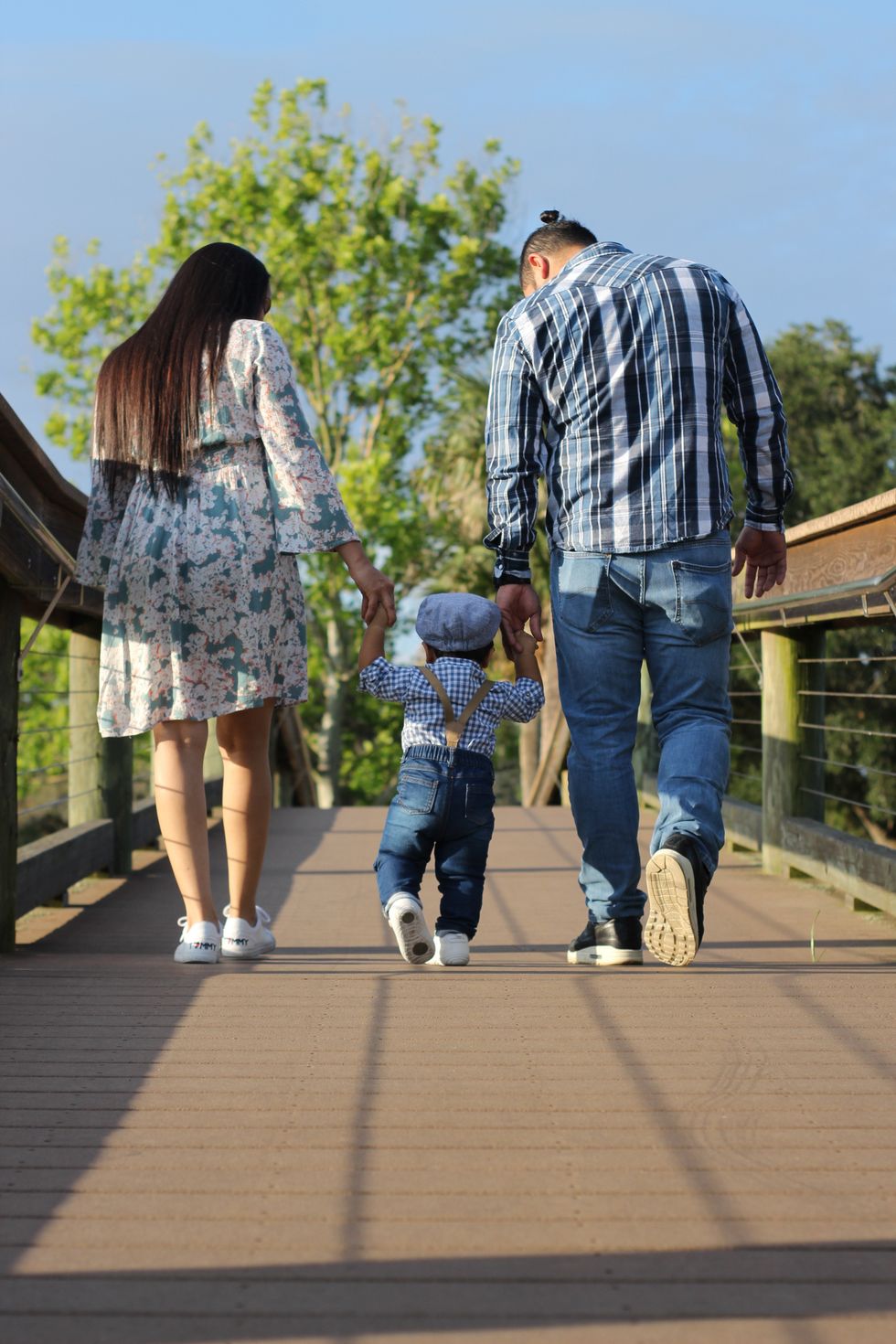 Couple holding young child's hand on a walk