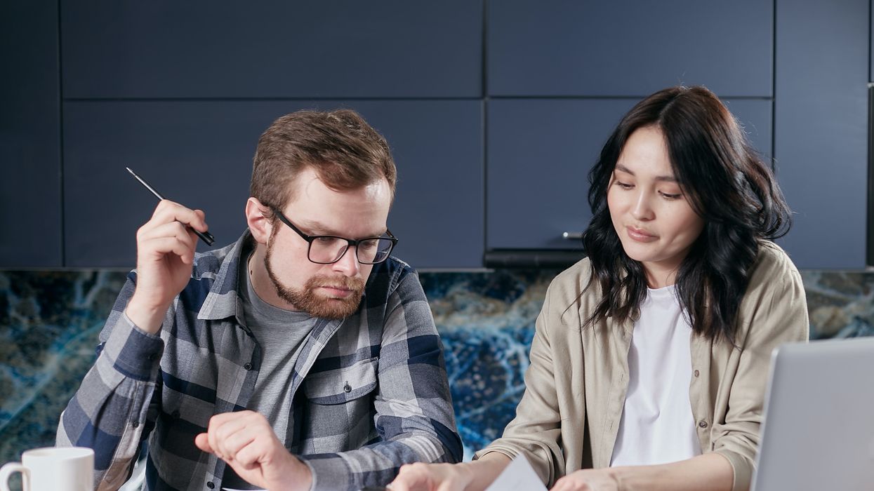 Couple look at finances with a laptop and calculator beside them