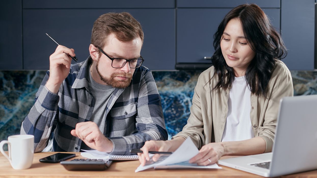 Couple look at finances with a laptop and calculator beside them