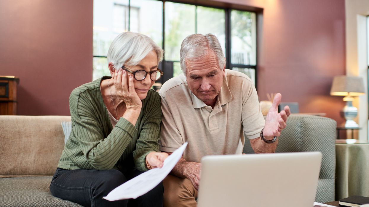 Couple look worried while on phone in front of laptop