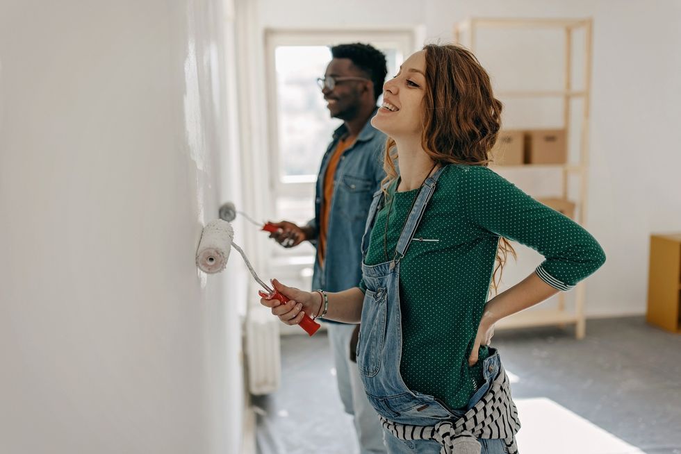 Couple painting their walls using grey paint