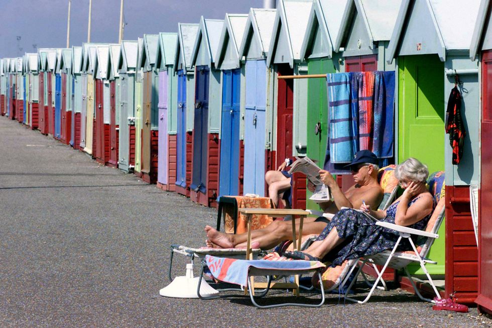Couple sunbathe outside Brighton beach huts