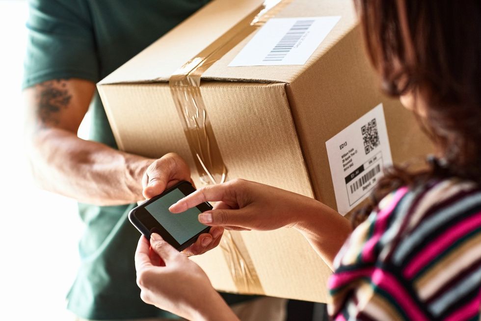 Courier handing over package asking female customer to do electronic signature, delivering, receiving, efficiency