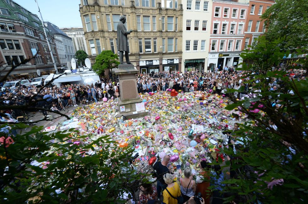 Crowds look at the floral tributes after a minute's silence in St Ann's Square, Manchester, to remember the victims of the terror attack in the city earlier this week.