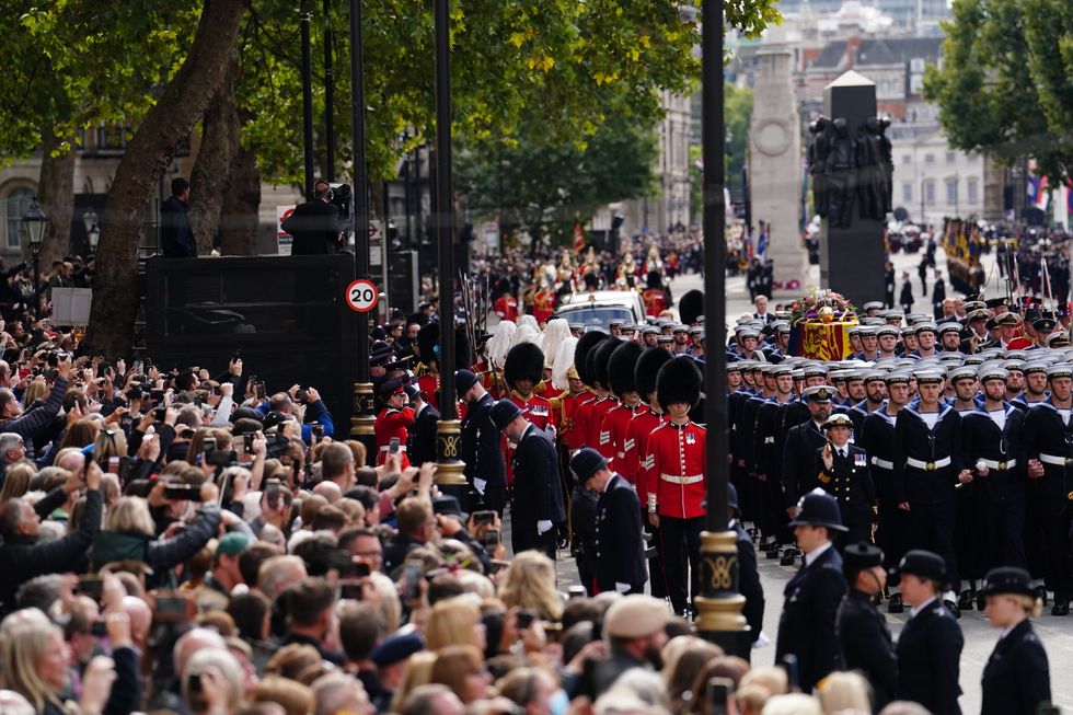 Crowds watch as the State Gun Carriage carries the coffin of Queen Elizabeth II, draped in the Royal Standard with the Imperial State Crown and the Sovereign's orb and sceptre, in the Ceremonial Procession following her State Funeral at Westminster Abbey, London. Picture date: Monday September 19, 2022.