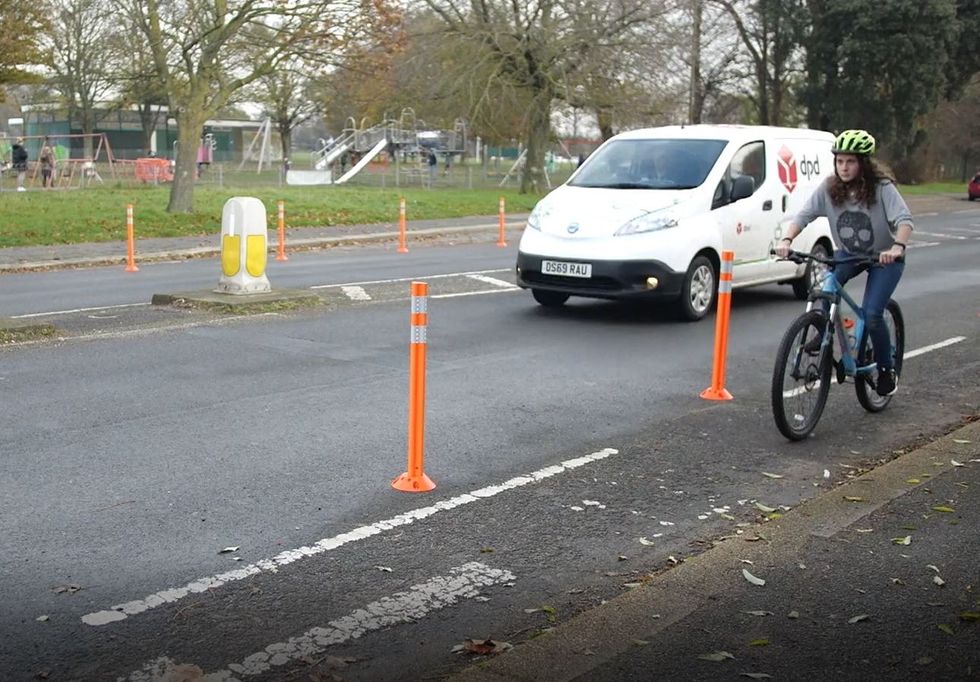 Cyclist cycling in cycle lane while DPD van drives beside her