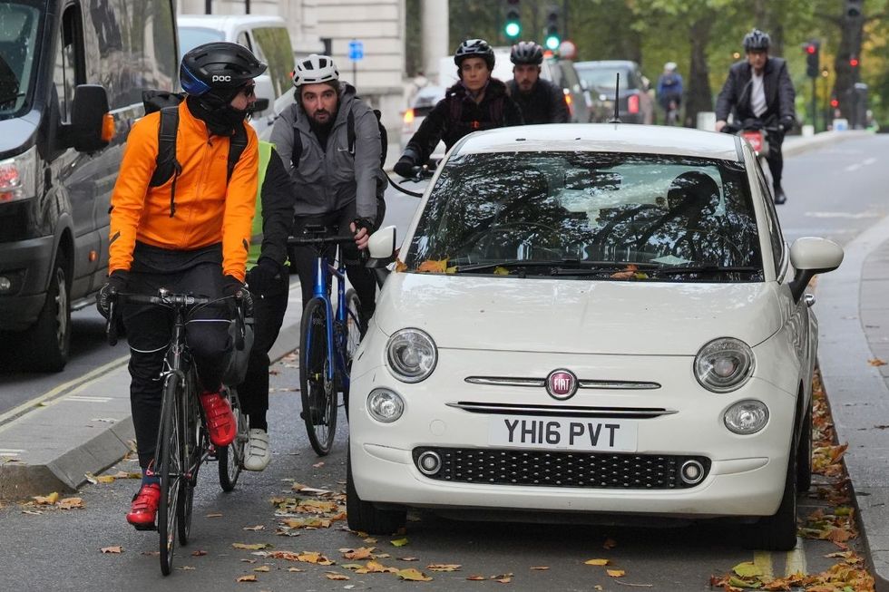 Cyclists riding past a car
