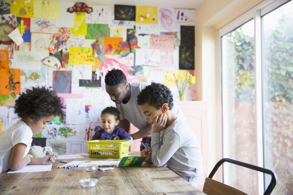 Dad and parents doing arts and crafts, children's artwork hanging in background