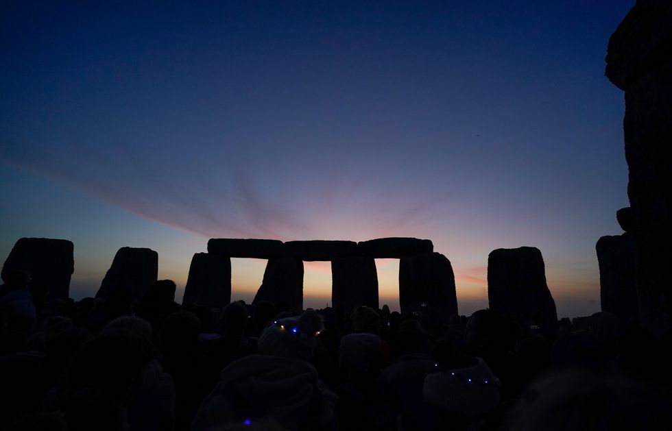 Dawn breaks behind the stones during the Summer Solstice at Stonehenge in Wiltshire. Picture date: Tuesday June 21, 2022.