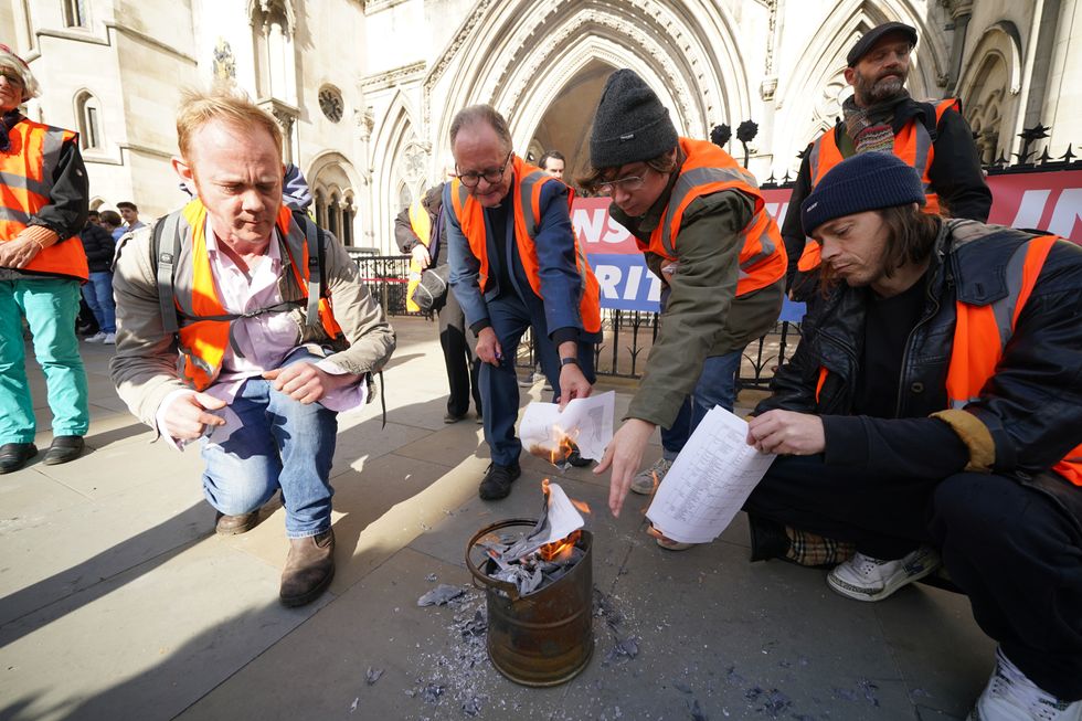 Demonstrators from Insulate Britain outside the High Court, central London, burn pages from court injunctions they have been individually served ahead of a hearing over three injunctions granted to National Highways in late September and October, covering the M25, Port of Dover and major A roads around London. Picture date: Tuesday October 12, 2021.