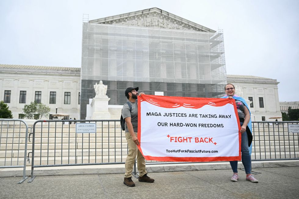 Demonstrators hold a banner outside the US Supreme Court, on the final day of the Court's term, in Washington, DC