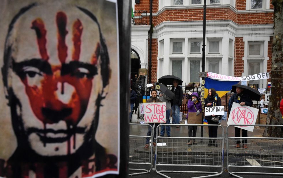 Demonstrators hold protest placards, with a depiction of Russian President Vladimir Putin seen in front, opposite the Russian Embassy in London, Britain, March 1, 2022. REUTERS/Toby Melville