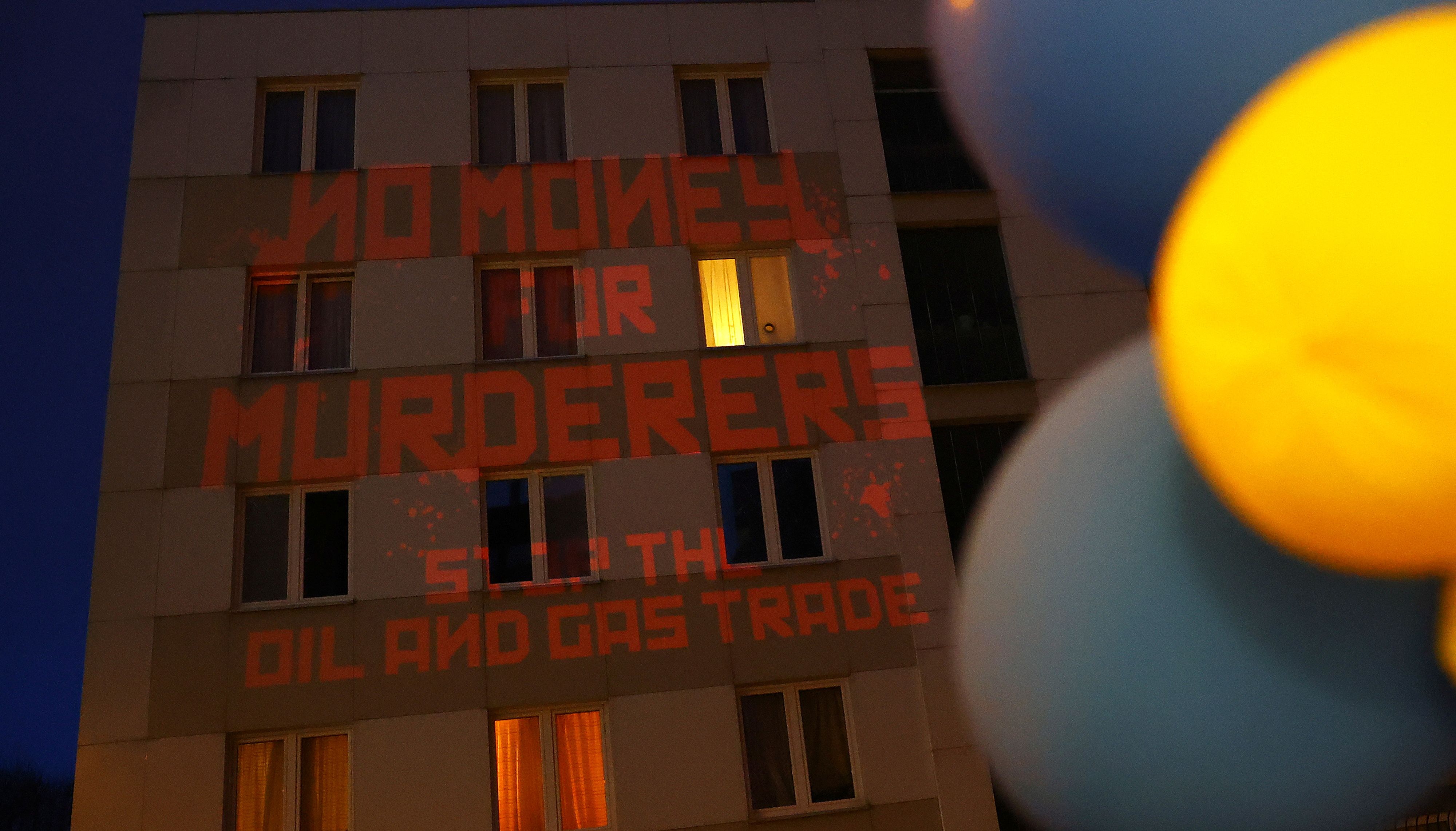 Demonstrators project the message reading %22No money for murderers, stop the oil and gas trade%22 on the general consulate building wall of the Russian Federation in Frankfurt, Germany.