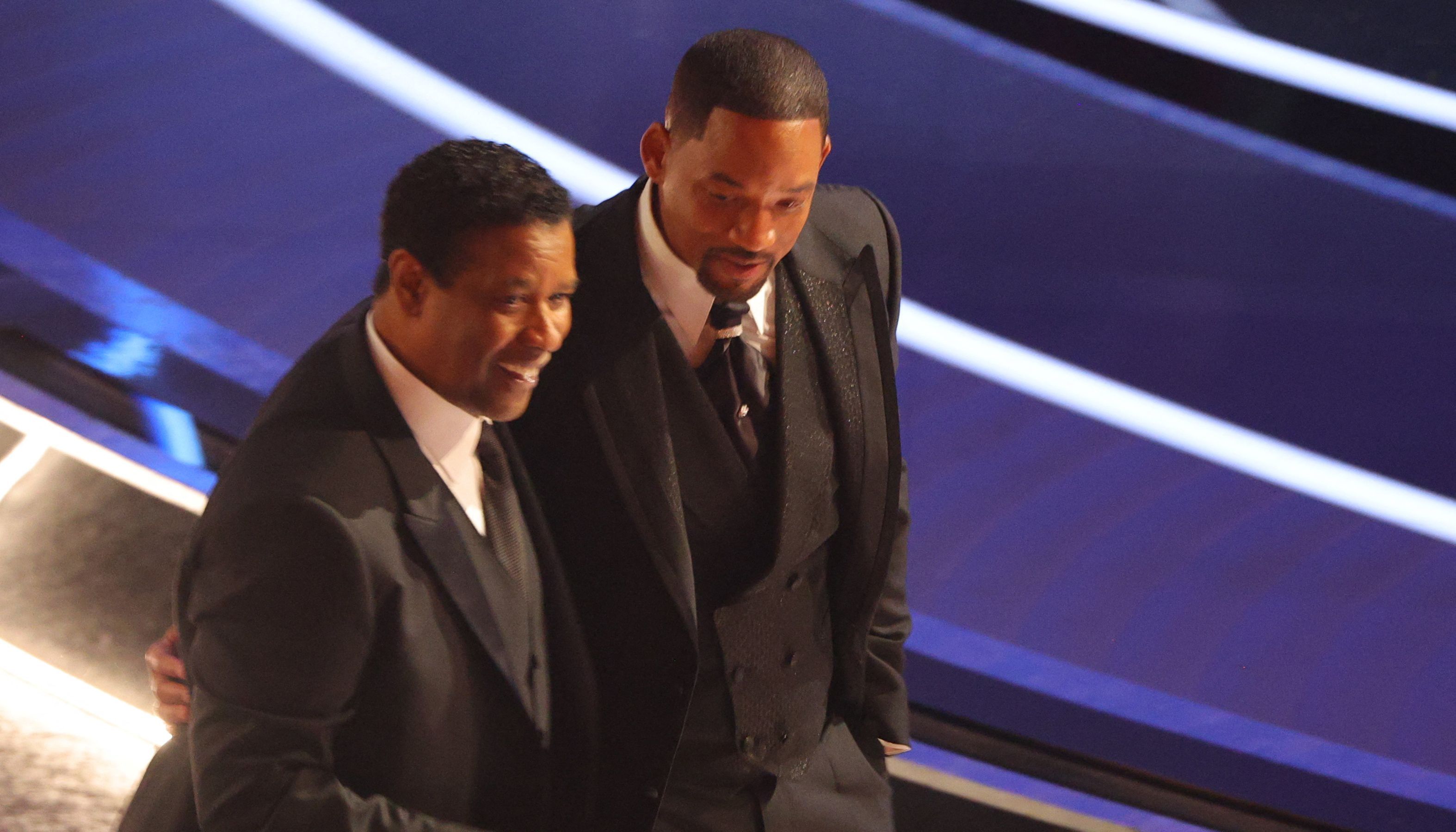 Denzel Washington (L) walks with Will Smith after Smith hit Chris Rock (not pictured) as Rock spoke on stage during the 94th Academy Awards in Hollywood, Los Angeles, California, U.S., March 27, 2022. REUTERS/Brian Snyder