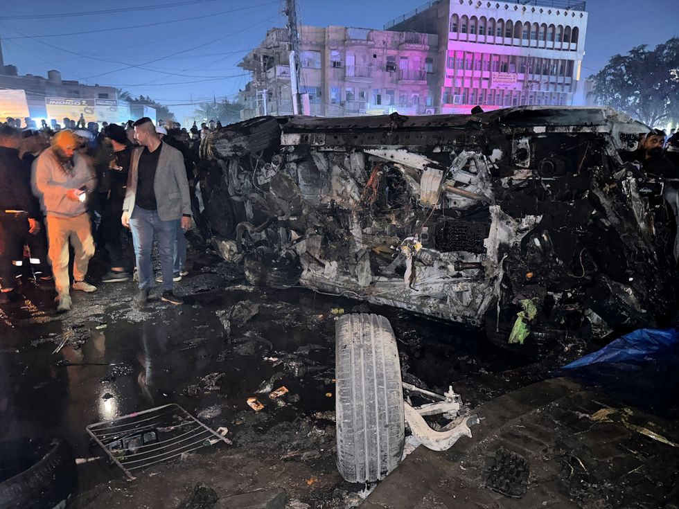 Destroyed vehicle with crowds